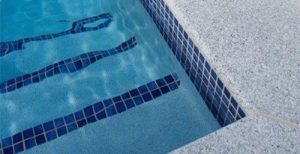 The salt & pepper tile from Sareen Stone used around a swimming pool