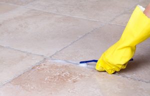 A photo of someone cleaning grout with a toothrbush and vinegar and bicarb soda