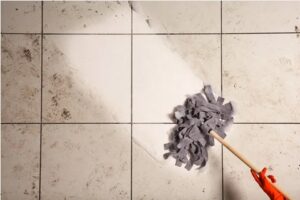 Person moping dirt off their bathroom floor ceramic tiles